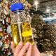 A photo of a sample of Quantafuel oil in front of a pile of waste.